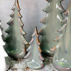 three ceramic christmas trees sitting next to each other on top of snow covered flooring