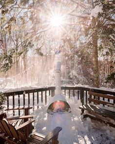 the sun shines brightly through the trees and snow on a deck with wooden benches