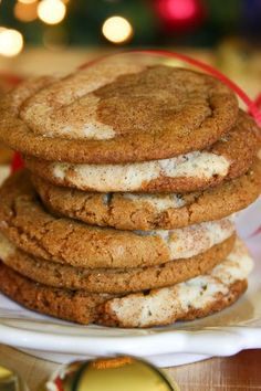 a stack of cookies sitting on top of a white plate next to a christmas tree