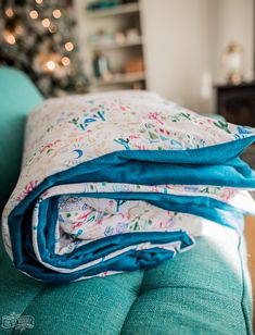 three folded blankets sitting on top of a couch next to a christmas tree in the living room