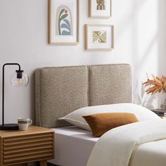 a bed with white sheets and brown pillows in a bedroom next to a lamp on a nightstand