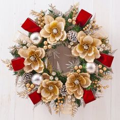 a christmas wreath with pine cones and red bows on a white wooden background is shown