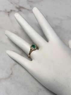 A Classic and Beautiful 14kt Yellow Gold Lady's Diamond and Emerald Ring consisting of a 5mm round genuine Emerald gemstone 3/4ct approx total weight set wtih 4 prongs in center surrounded by a halo of full cut round faceted diamonds .15ct approx total weight all prong set in finger size 6 3/4. May is the Birthstone for Emerald. This item would Retail for $2,550.00 Emerald Diamond Ring With Diamond Accents, Emerald Rings With Diamond Accents Round Cut, Formal May Birthstone Diamond Ring With Round Band, Formal Round Diamond Ring For May Birthstone, Classic Emerald Ring With Diamond White Color, Diamond May Birthstone Ring With Center Stone, Diamond Birthstone Ring With Center Stone For May, Fine Jewelry Round Emerald Diamond Ring, Diamond Cluster Ring With Brilliant Cut For May Birthstone