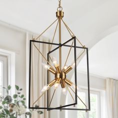 a chandelier hanging from the ceiling in a room with white walls and windows