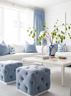 a living room with blue and white decor on the couches, coffee table and ottomans