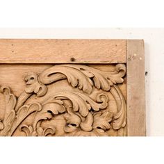 an intricate carved wood panel with flowers and leaves on it's sides, mounted against a white wall