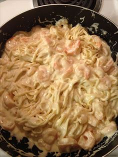 pasta with shrimp and sauce in a skillet on the stove top, ready to be cooked