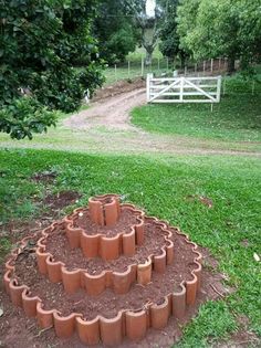 a circular garden design made out of clay bricks in the middle of a grassy area