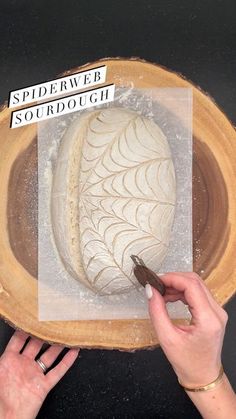 a person is carving something on top of a wooden bowl with white frosting in it