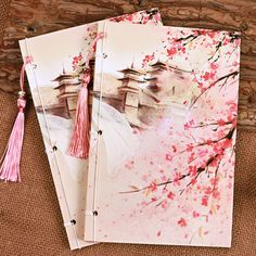 three notebooks with pink flowers and tassels sitting on top of each other