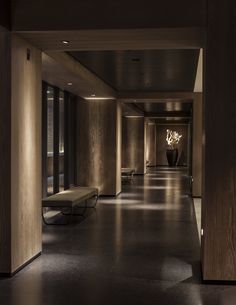 an empty hallway with benches and lights on the side wall, along with large windows