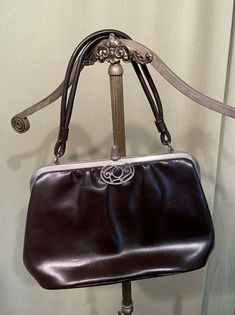 "This is a lovely, vintage brown, faux leather handbag purse from the 50s or early 60s. No labels or tags. The purse has a single compartment, with a zipper pocket on 1 side. The purse is a faux leather hand bag with silver tone metal frame. Lined with brown vinyl. It has a single, doubled handle. Trimmed with a pierced metal oval. The bag measures 6.5\" tall and 10\" wide & 3\" across the bottom. The strap drop measures 5-1/2\". It is in good, vintage condition, showing minimal soil and min Early 60s, Faux Leather Handbag, Vintage Purses, Knit Wrap, Vintage Floral Print, The 50s, Star Charms, Handbag Purse, Vintage Bags