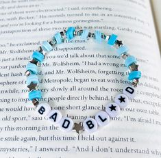 a bracelet with beads that spell out the word bad to be on top of an open book