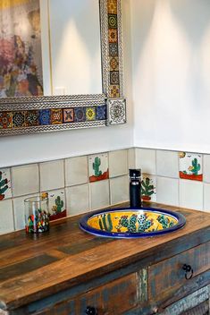 a bathroom sink sitting under a mirror next to a wooden counter