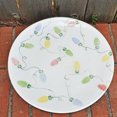 a white plate with christmas lights painted on it