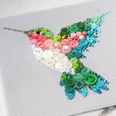 a colorful bird made out of buttons on a piece of paper with bead work