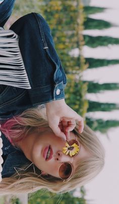 a woman with pink hair and sunglasses holding a flower