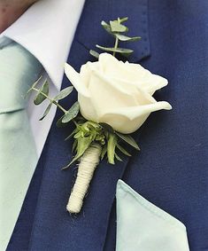 a man wearing a blue suit and tie with a white rose boutonniere