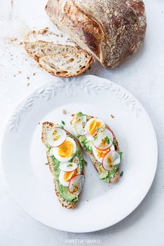 an open faced sandwich with hard boiled eggs on it and sliced bread in the background