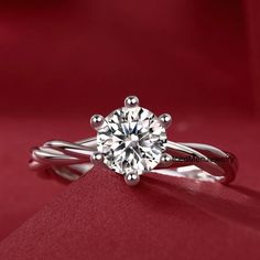 a white gold engagement ring with a round brilliant diamond in the center on a red cloth