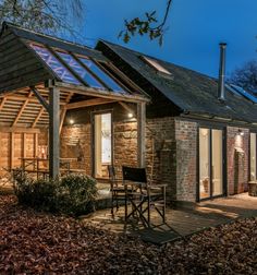 a small brick building with a glass roof and patio area at night in the fall