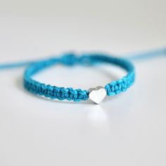 This bracelet is made of turquoise waterproof rope and a silver plated heart charm. Blue Heart Charm Jewelry For Friendship, Handmade Turquoise Heart Bracelet, Handmade Turquoise Heart Bracelet As A Gift, Handmade Turquoise Heart Bracelet As Gift, Silver Heart Friendship Bracelets, Silver Heart-shaped Friendship Bracelets, Handmade Turquoise Heart Bracelet For Gift, Adjustable Blue Bracelet With Heart Charm, Turquoise Bracelet With Heart Charm For Gifts