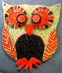 an orange and black owl made out of plastic on top of a gray tablecloth