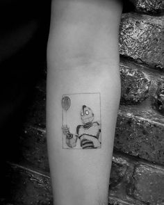 a person with a tattoo on their arm holding a balloon and a cat in the background