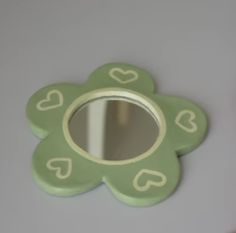 a green flower shaped mirror sitting on top of a counter next to a wall mounted toothbrush holder