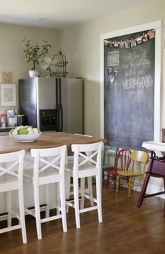 a kitchen table with chairs around it and a chalkboard on the wall