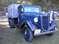 an old blue truck is parked in the grass