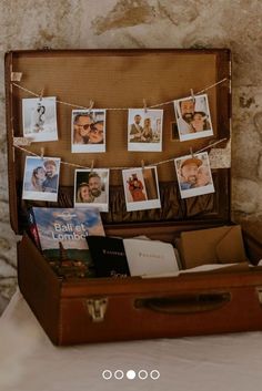 an open suitcase sitting on top of a bed next to pictures hanging from clothes pins