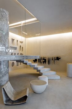 a room filled with lots of white furniture next to a stair case and wall mounted mirror