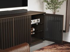 an entertainment center with speakers and a plant in the corner, next to a brown leather chair