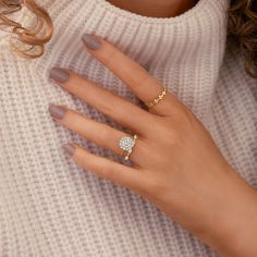 a woman's hand wearing a gold ring with a diamond on the middle finger