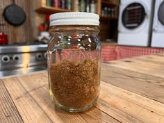 a jar filled with brown stuff sitting on top of a wooden table