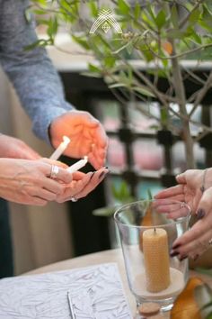 three people holding candles in their hands at a table with food and drinks on it