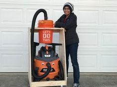 a woman standing next to an orange and black fire extinguisher in front of a garage door