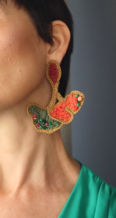 a woman wearing large earrings with colorful designs on them