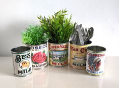 there are four tins with plants in them on the table next to each other