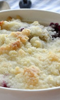 a close up of a bowl of food with blueberries and crumbs in it