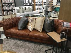 a brown leather couch with many pillows on it