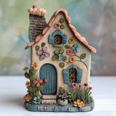 a ceramic house with flowers and plants around it