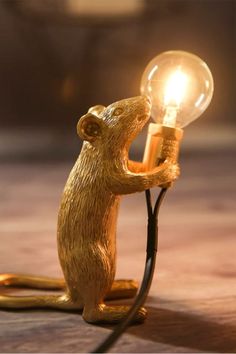 a lamp that is shaped like a rat holding a light bulb on it's back