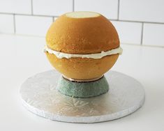 an egg on top of a cake sitting on a silver plate in front of a white tile wall