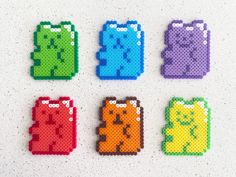 four different colored bears made out of perforated plastic beads on a white surface