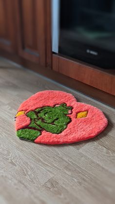 a pink rug with a green cartoon character on it sitting on the floor in front of a microwave