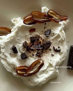 a white plate topped with whipped cream and toppings next to a bar of chocolate