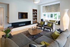 a living room filled with furniture and a flat screen tv mounted on the wall above a fireplace