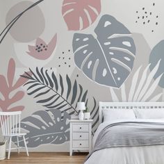 a white bed sitting next to a wall covered in plants and leaves on top of a wooden floor